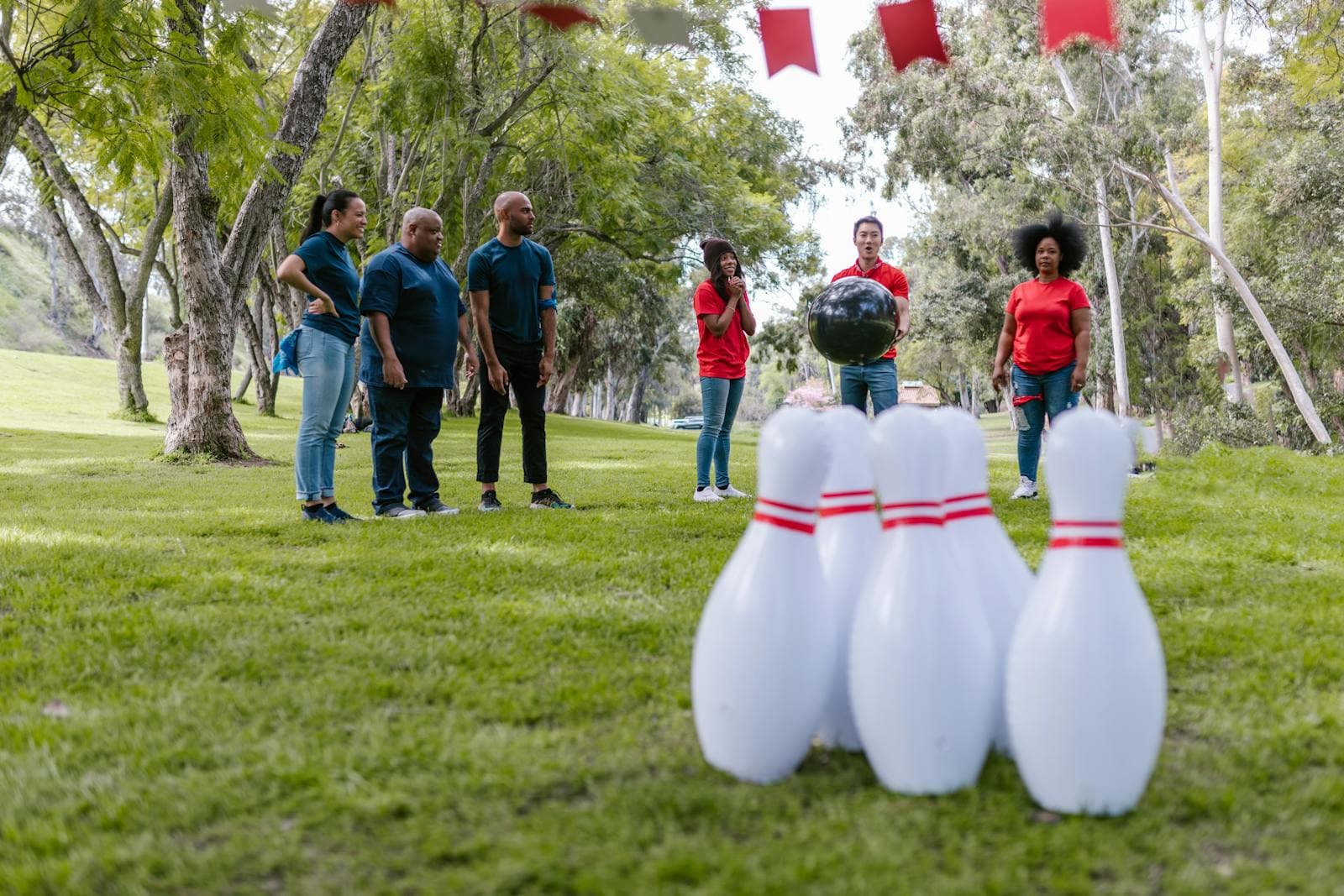 Group of diverse adults enjoying an outdoor bowling activity for team building in a park.