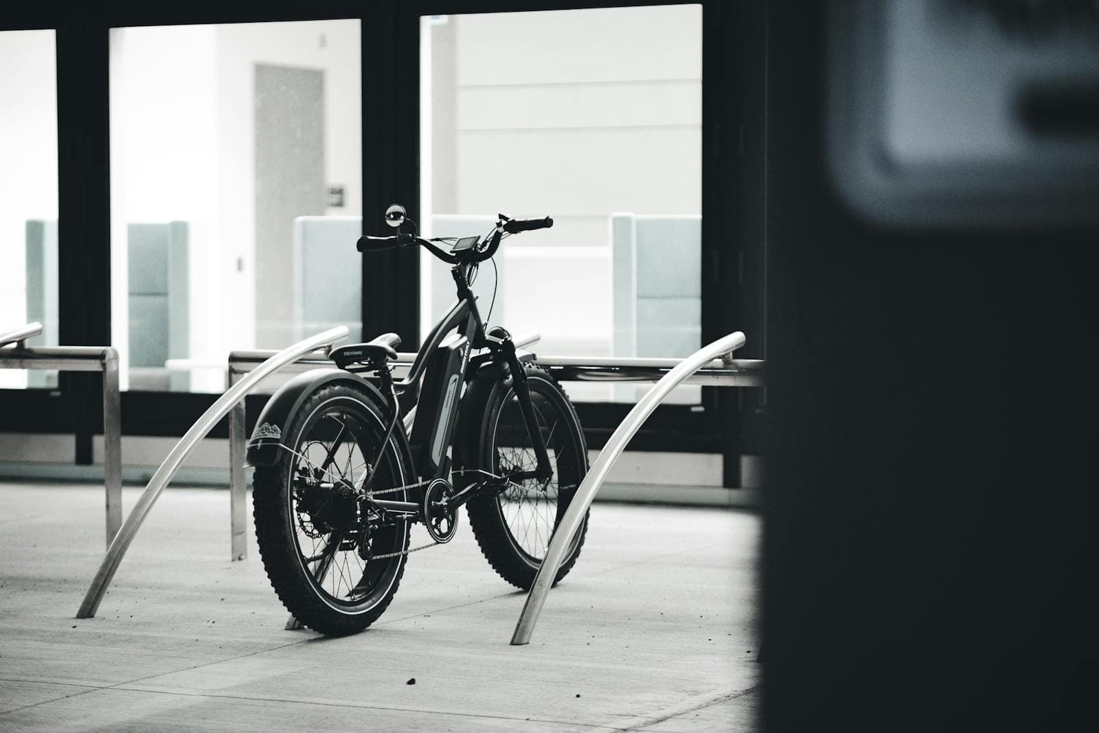Black and white image of an electric bicycle parked indoors in an urban environment.