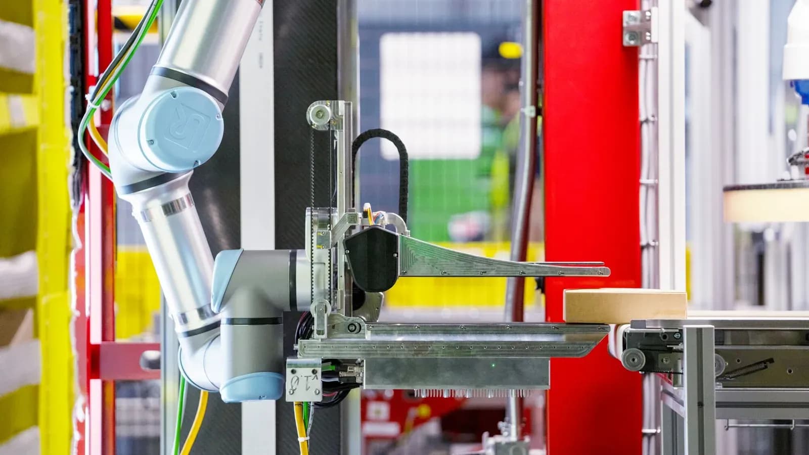 A robotic arm moves a package on a conveyor inside an Amazon facility.