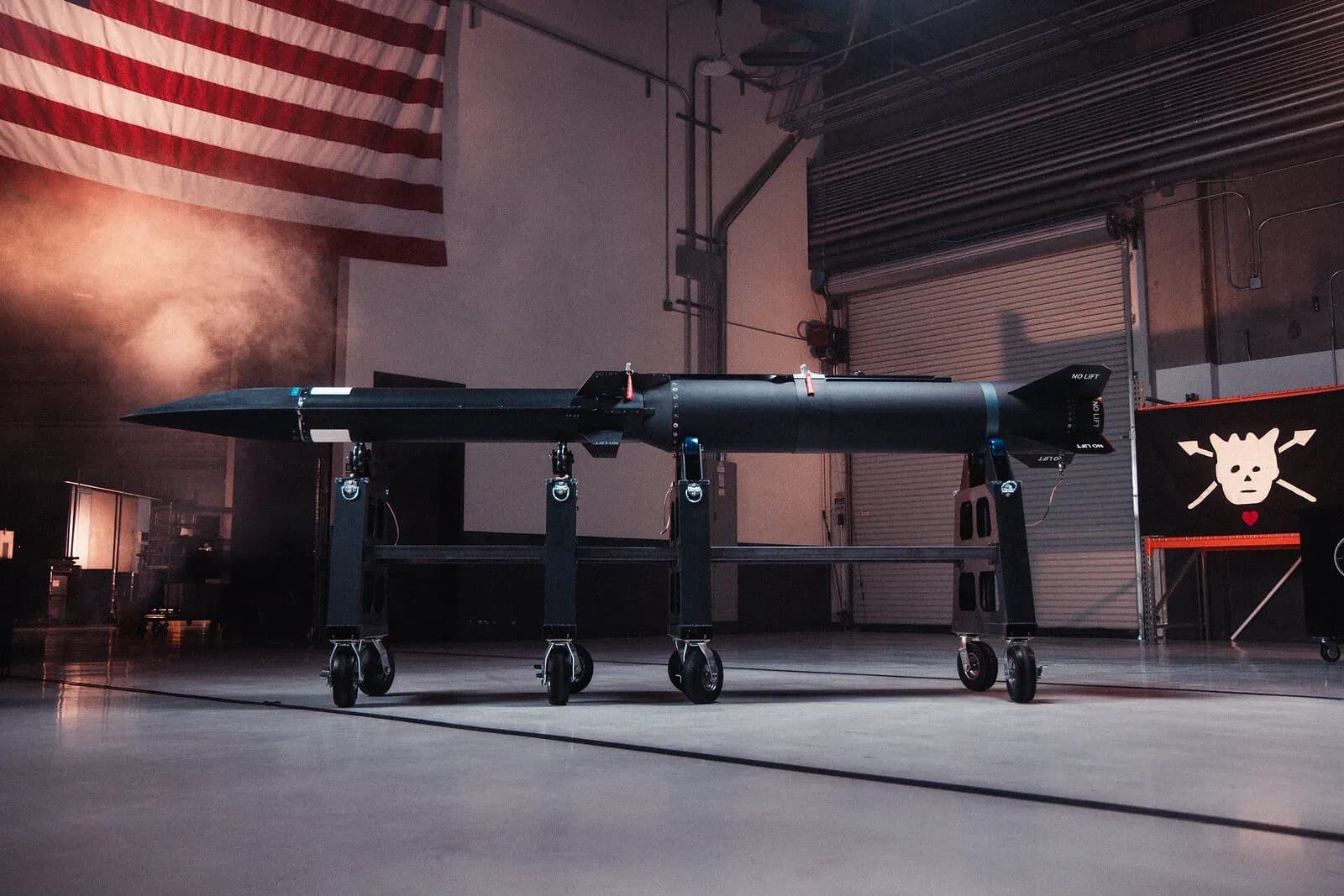 A black Blackbeard hypersonic missile on a wheeled cradle inside Castelion hangar with a US flag on the wall