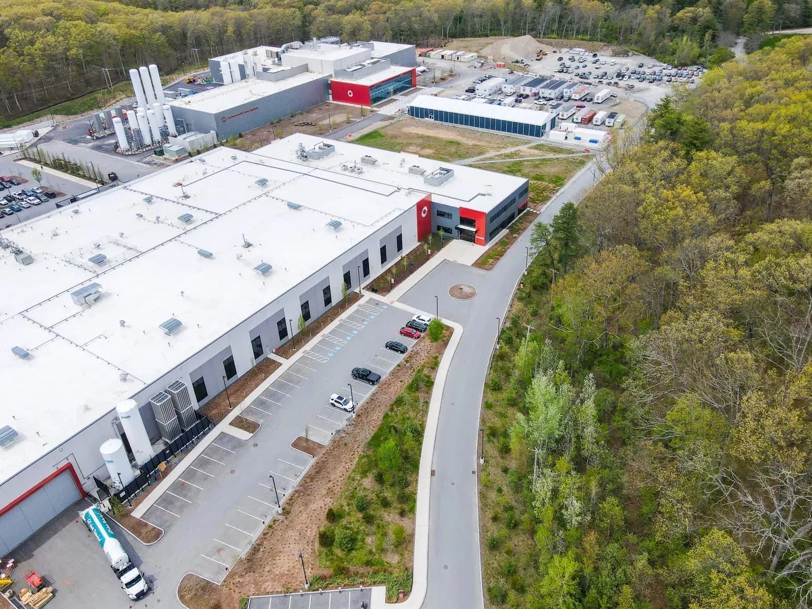 Aerial view of the Commonwealth Fusion Systems campus in Devens, Massachusetts, with assembly buildings and cryogenic tanks.