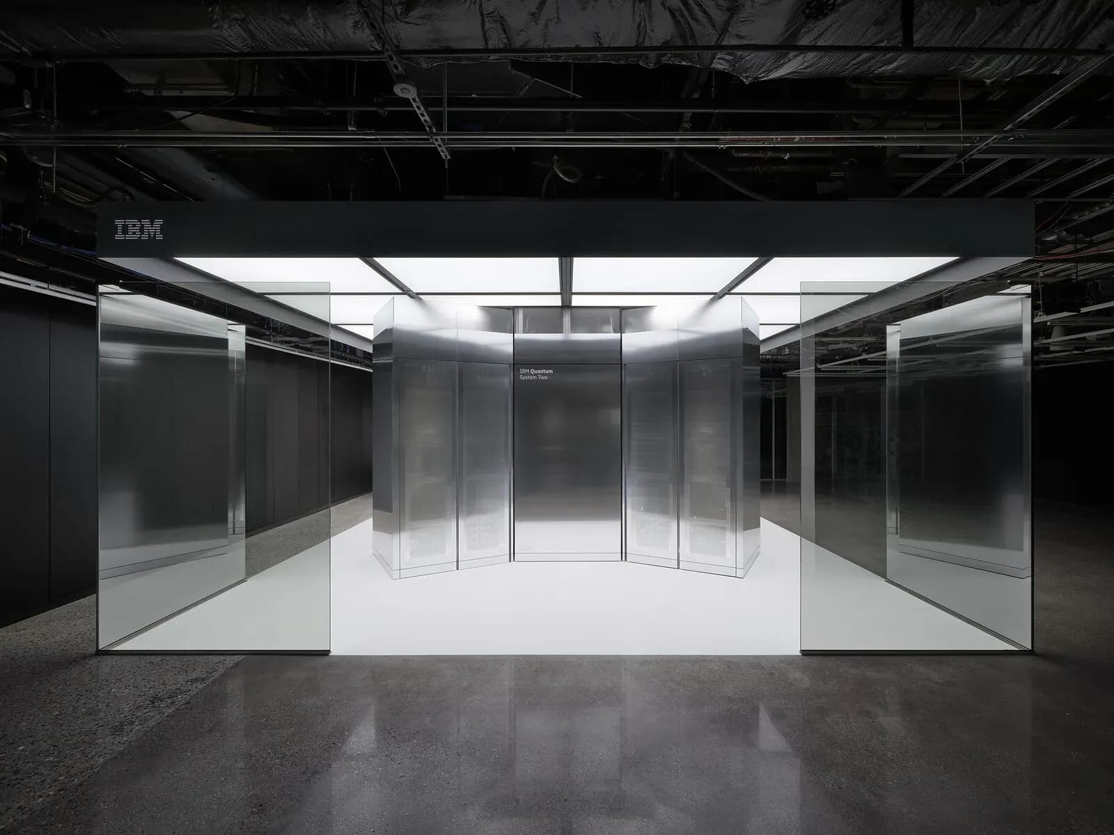 IBM Quantum System Two, a hexagonal cluster of cabinets behind glass panels in a data hall.