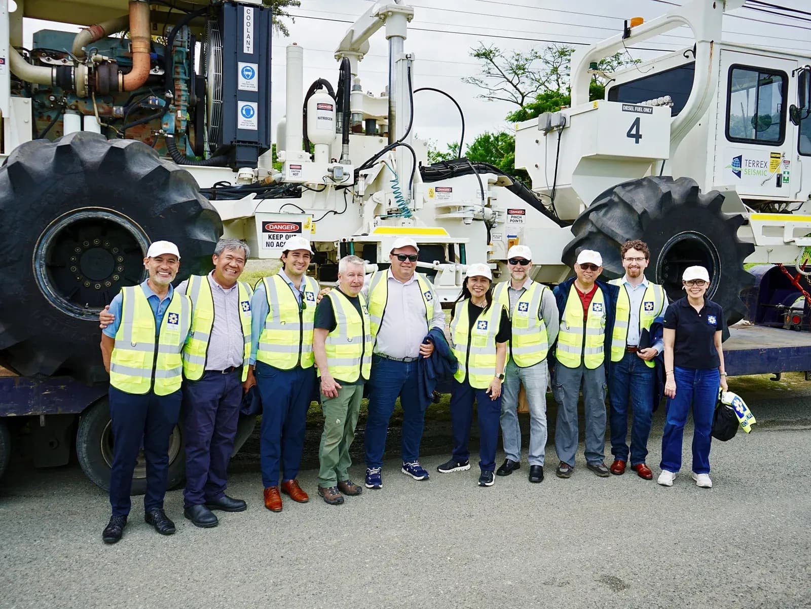 Koloma and partner personnel in high-visibility vests standing in front of a seismic survey vehicle in the Philippines
