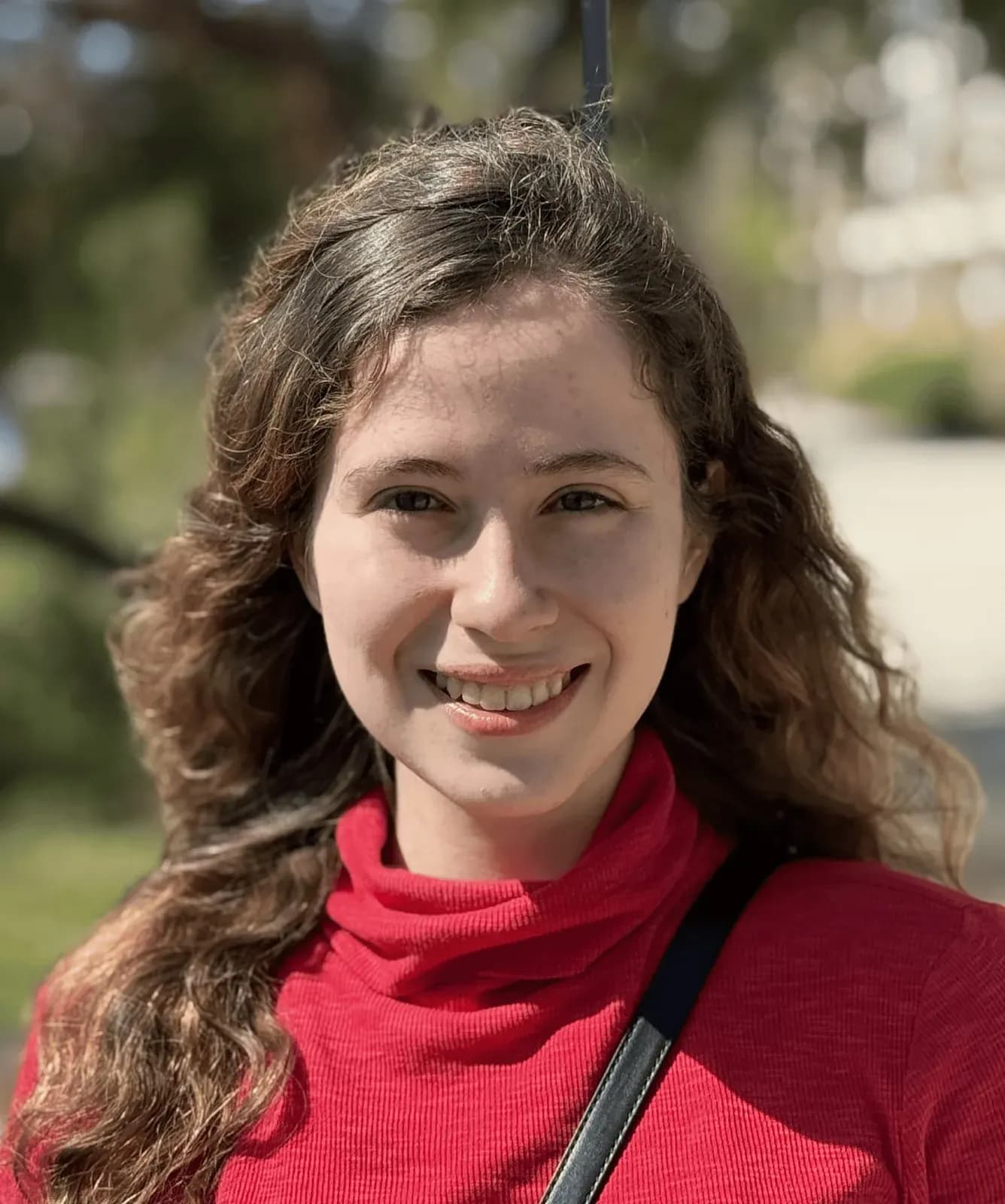 Naomi Bashkansky, founding researcher at Conduit, photographed outdoors in a red top