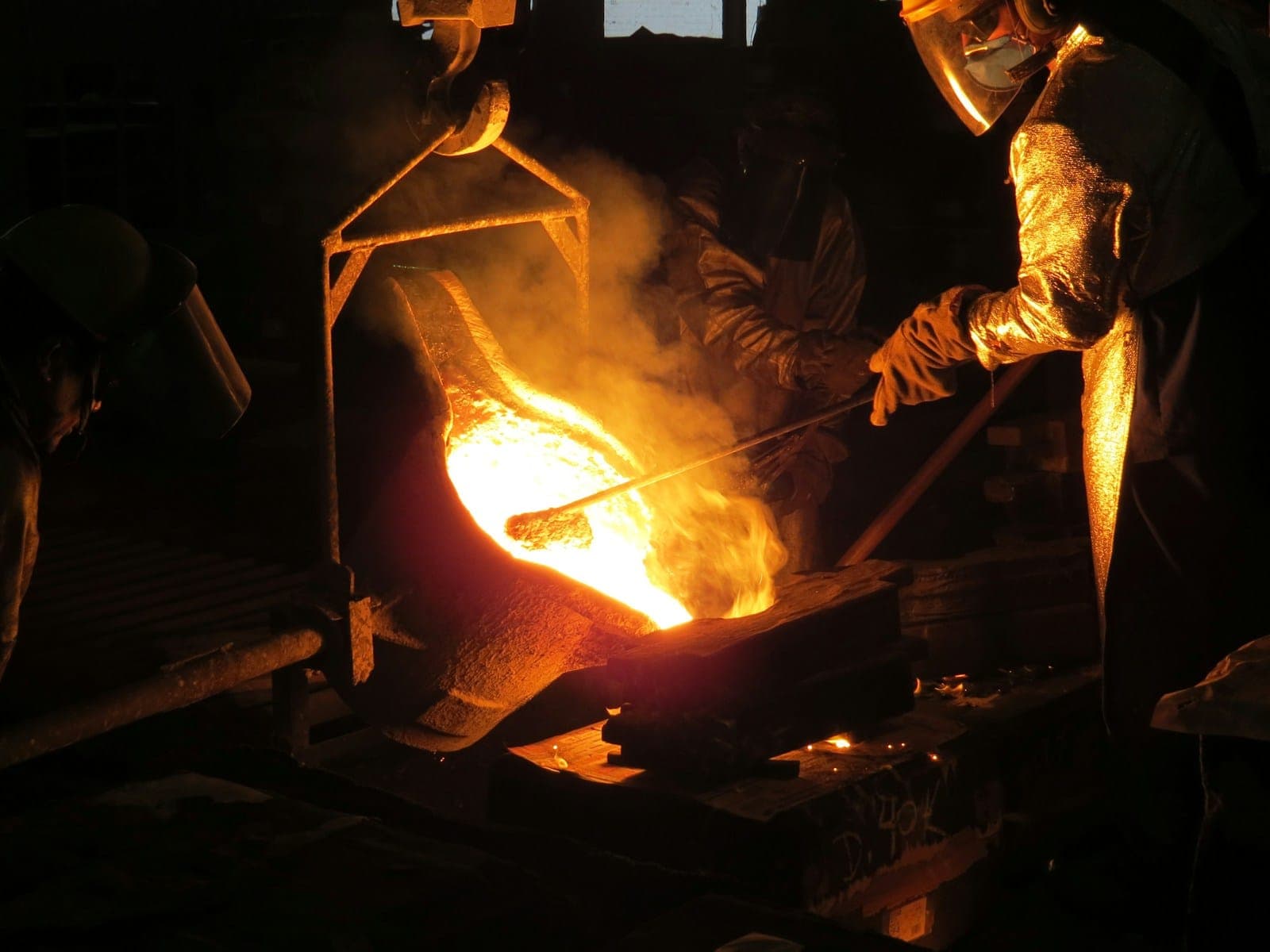 man wearing gloves and mask pouring molten metal