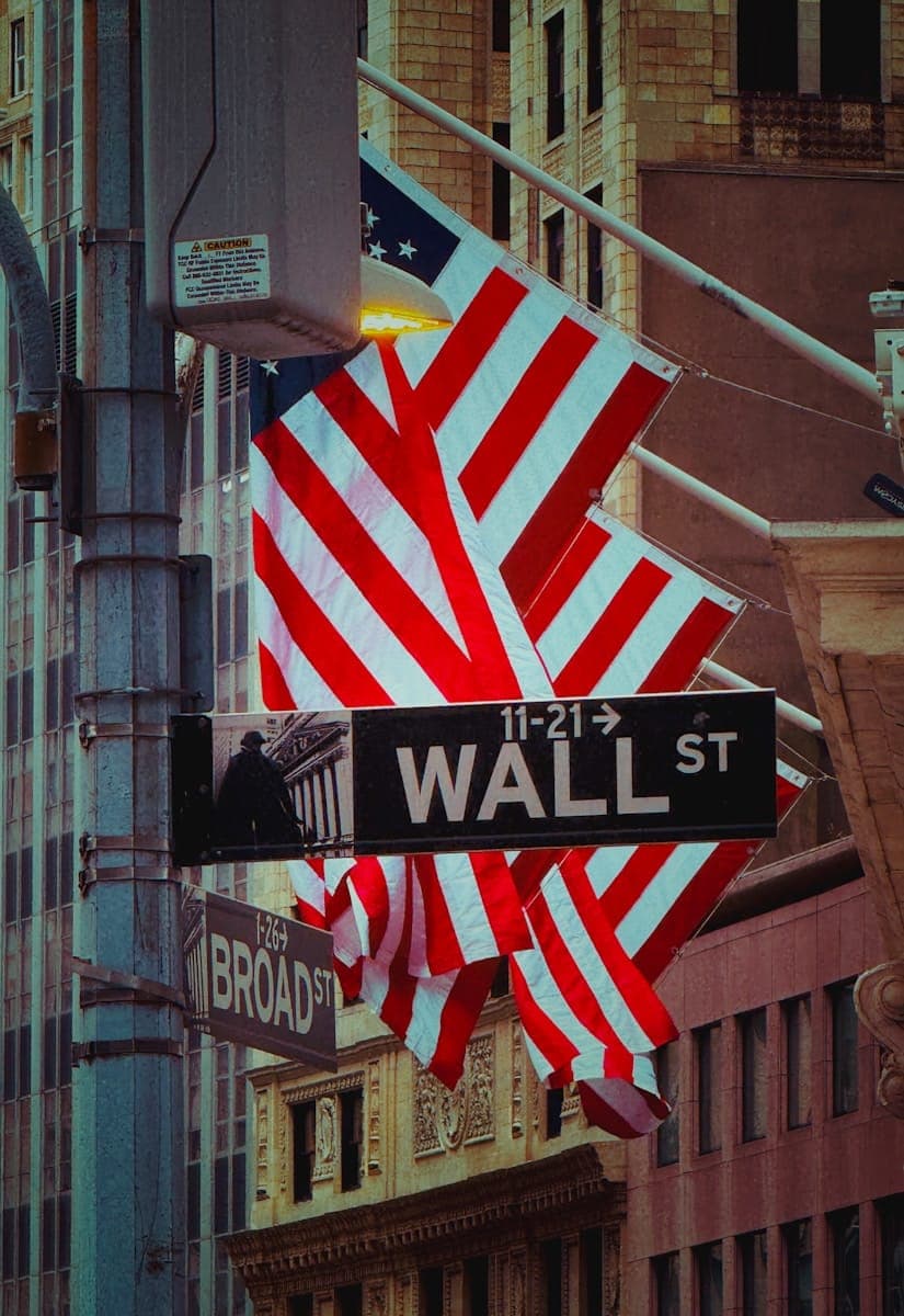 Wall street sign with flags waving.