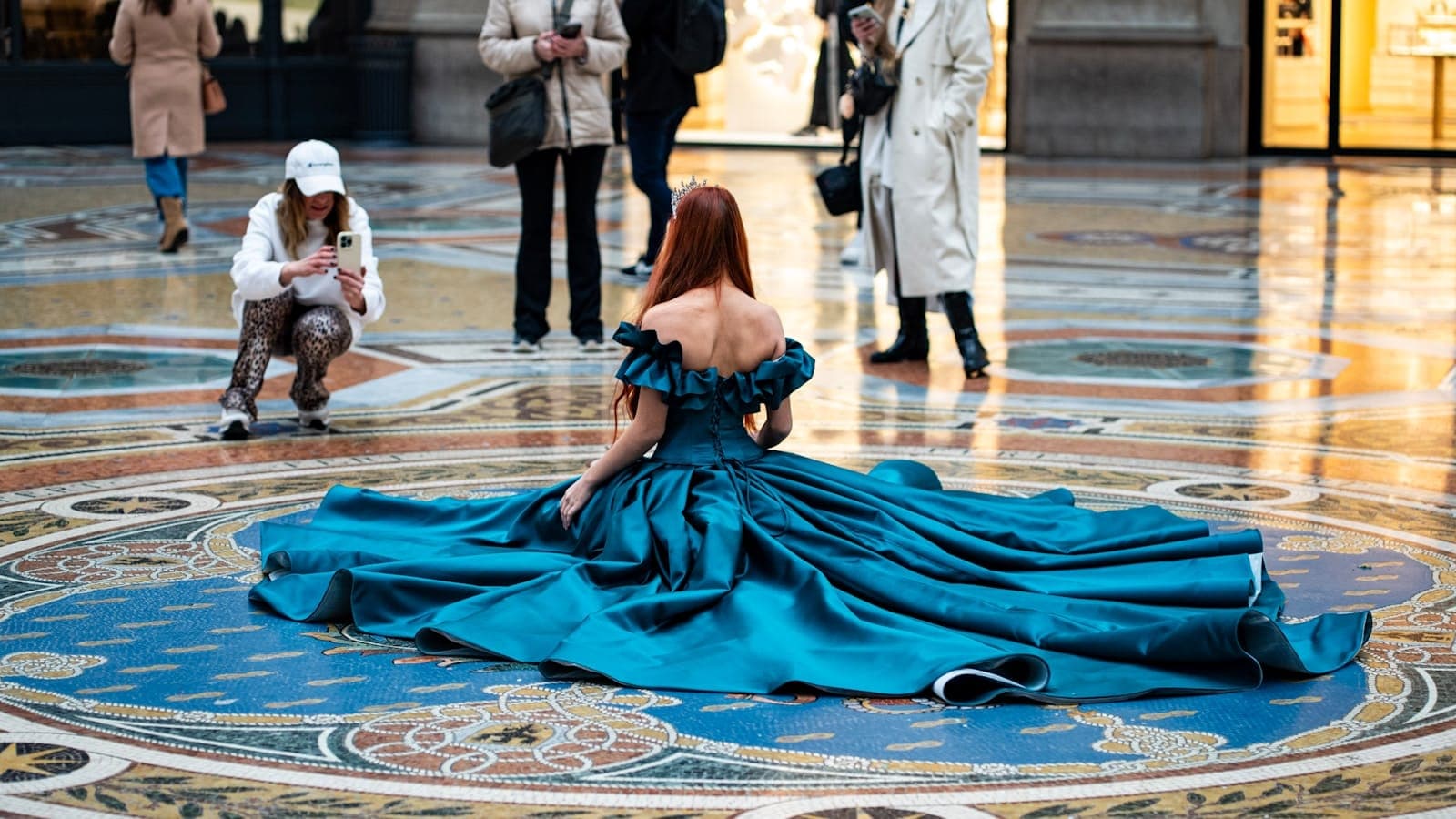 Woman in gown poses on a patterned floor.