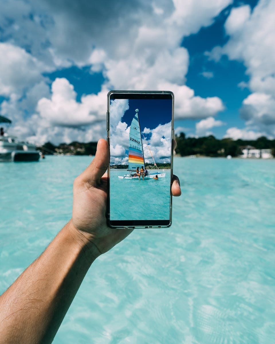 A vibrant smartphone display capturing a boat on turquoise waters under a bright blue sky.