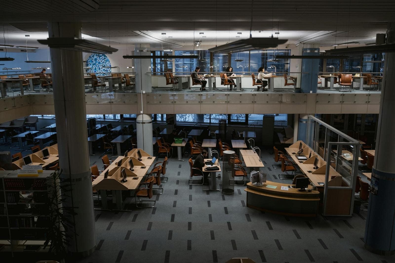 Spacious university library with study tables and people engaged in work.