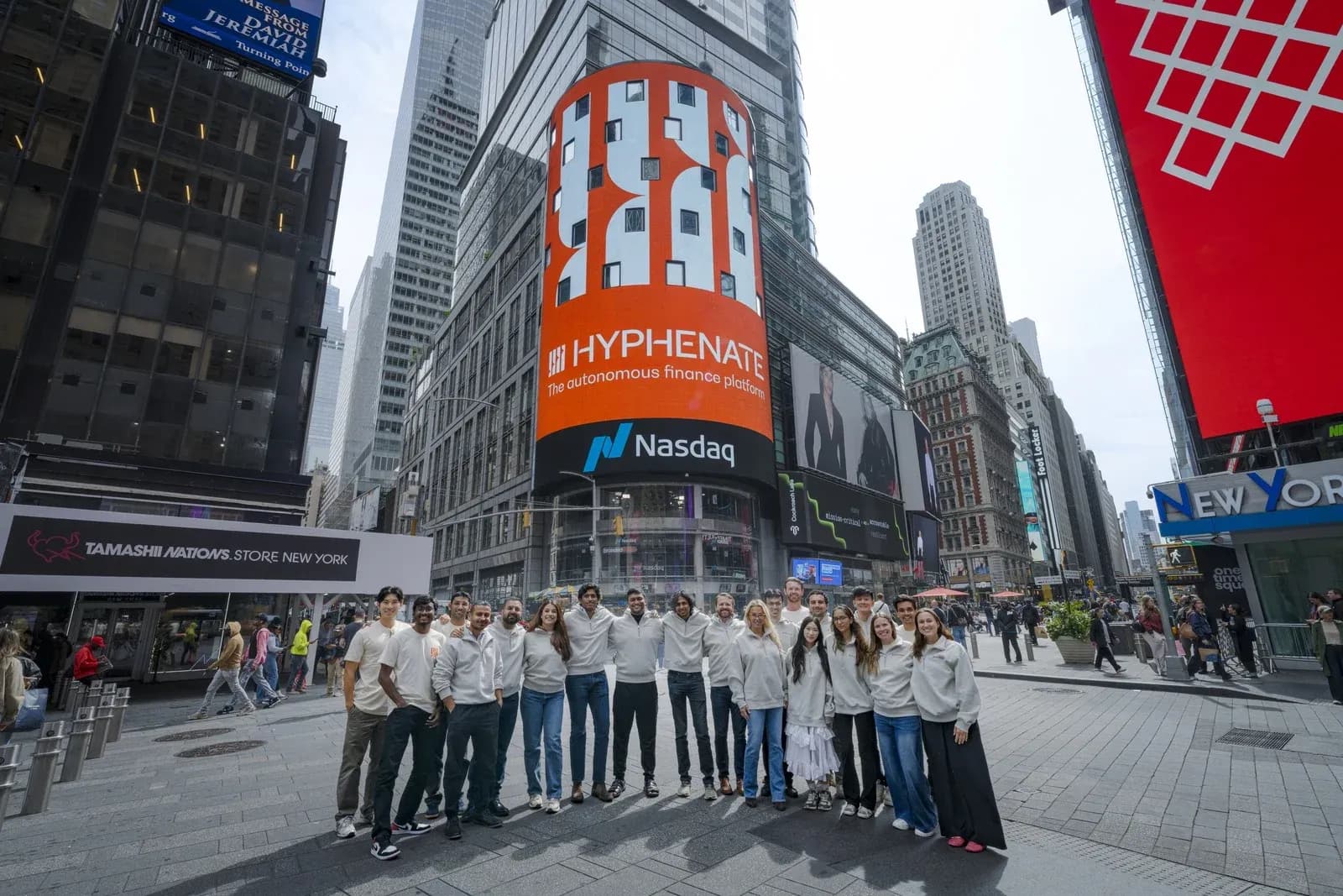 The Hyphenate team in Times Square, New York, below the company's new name on the Nasdaq tower screen