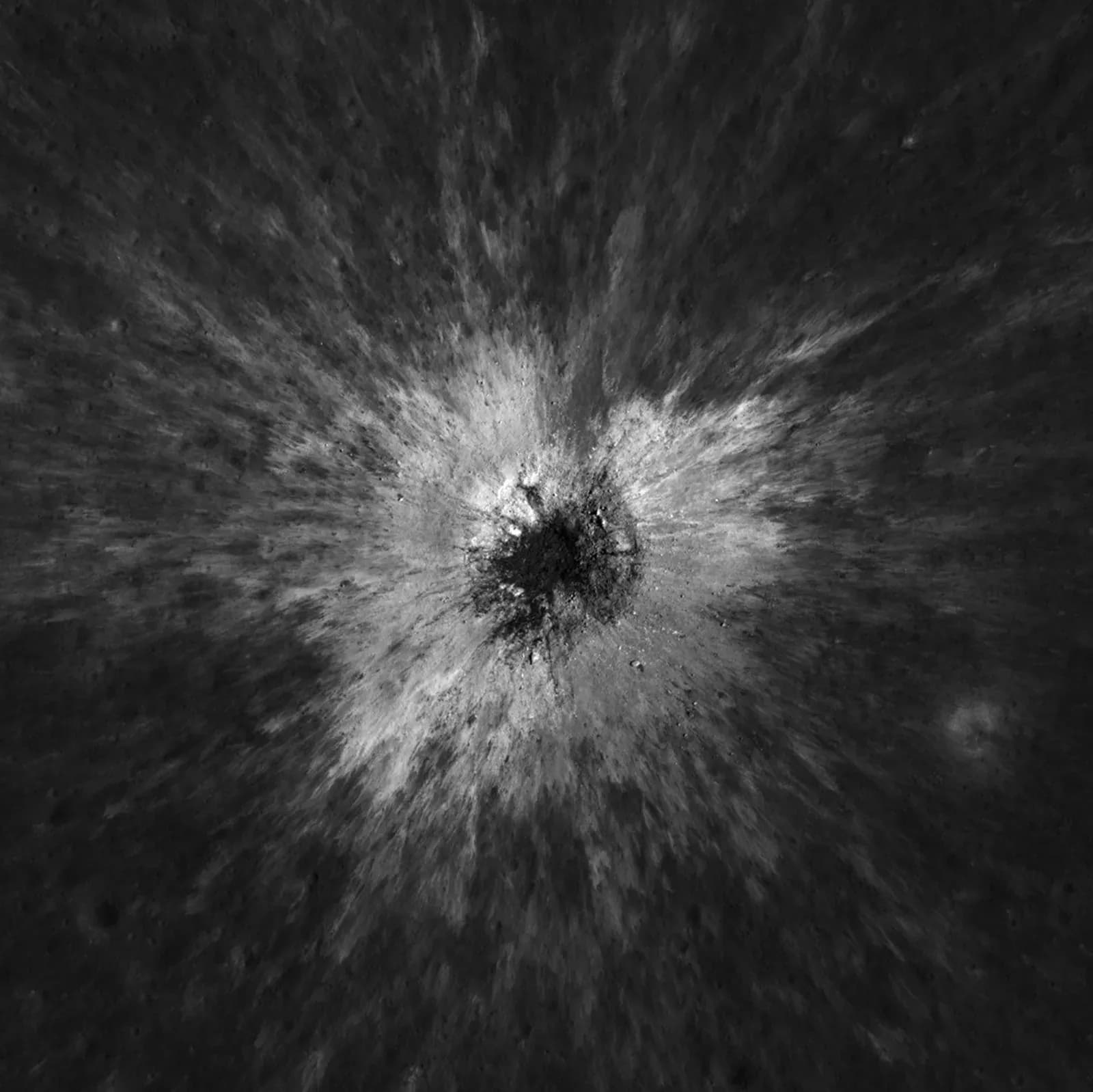 Overhead view of the fresh McGetchin crater on the Moon, a dark center ringed by bright ejecta rays across the grey lunar surface