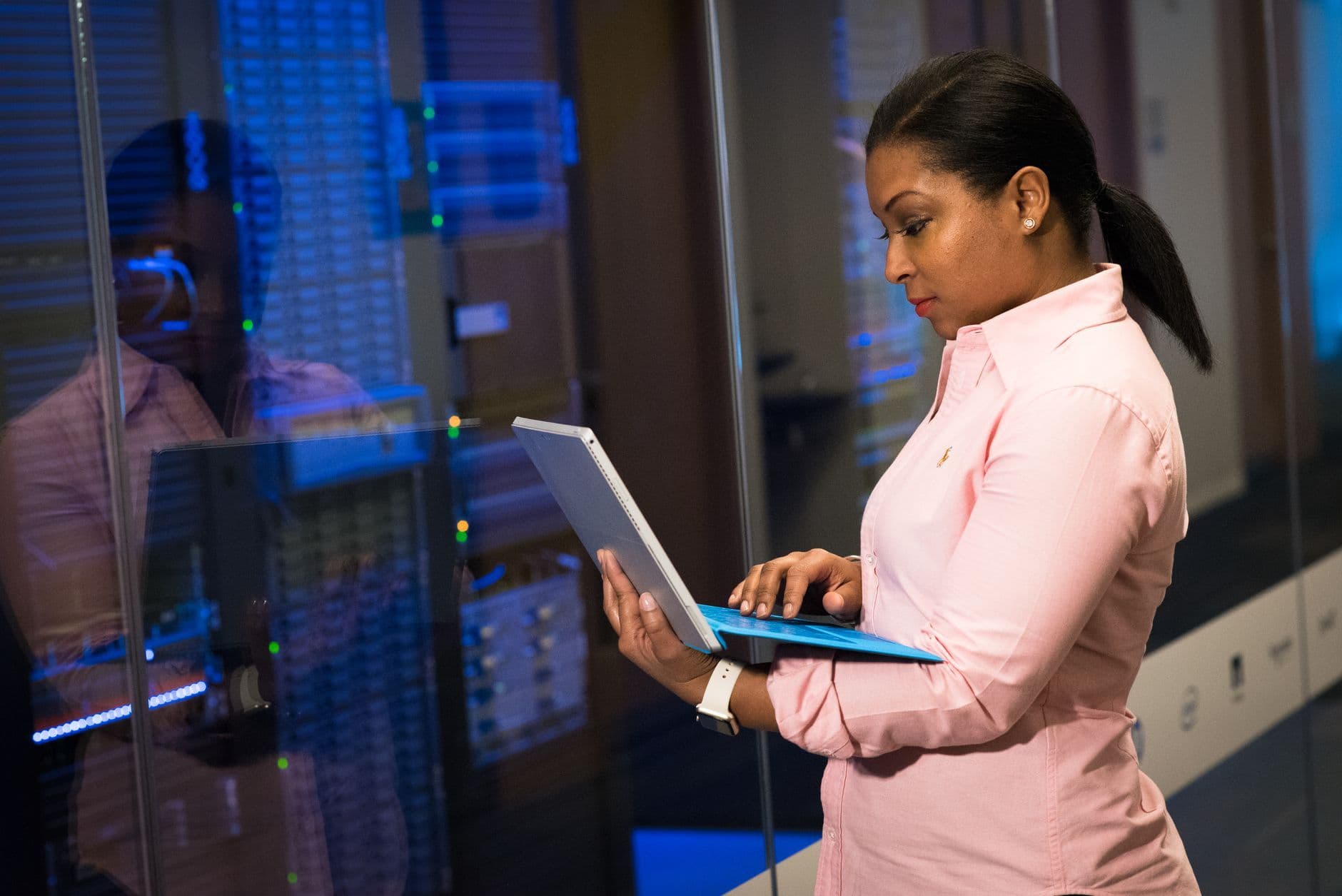 An engineer works on a laptop beside rows of server racks in a data center