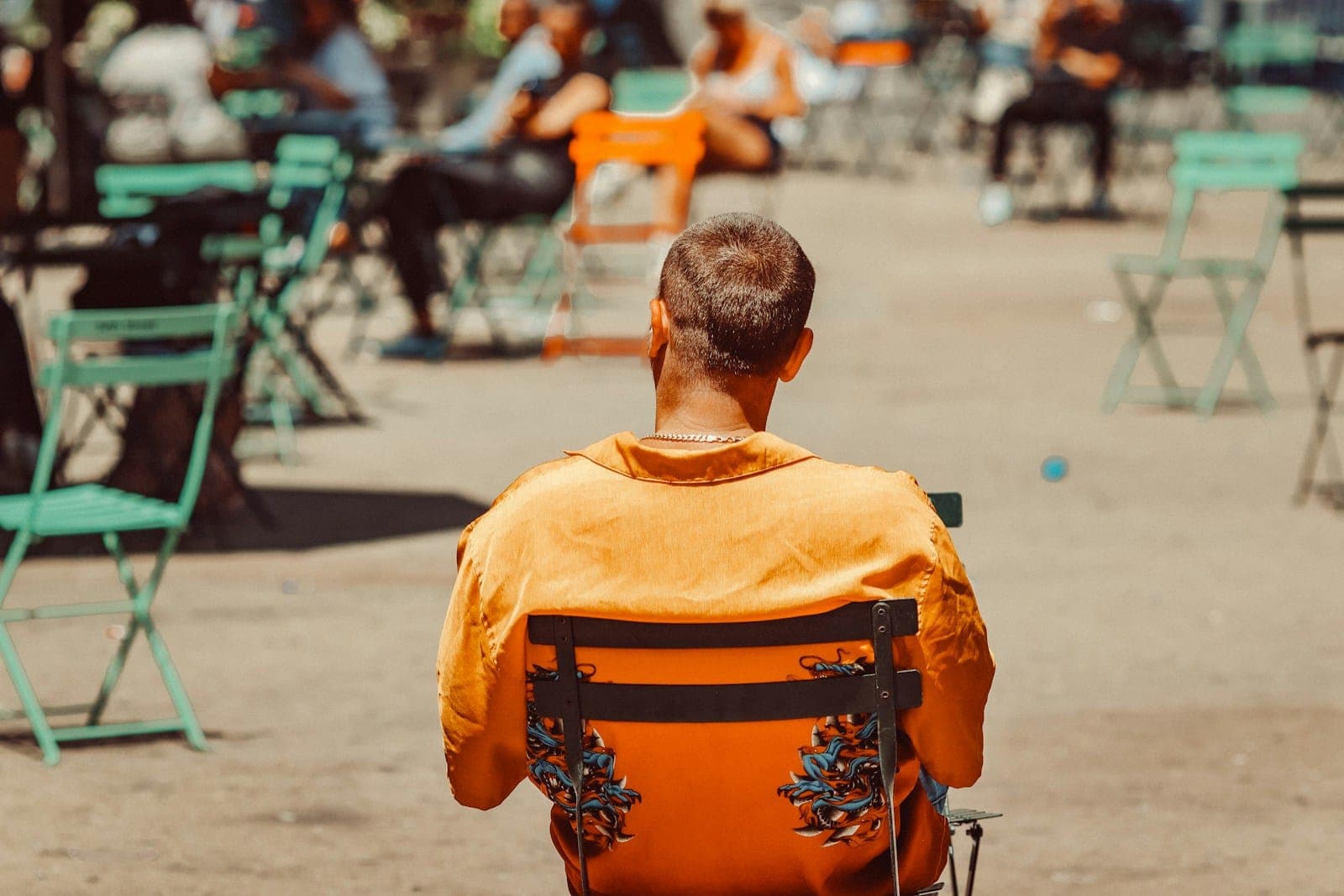 A man in an orange shirt is sitting in a chair