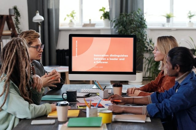 staff members sitting in front of a screen at a tech company meeting