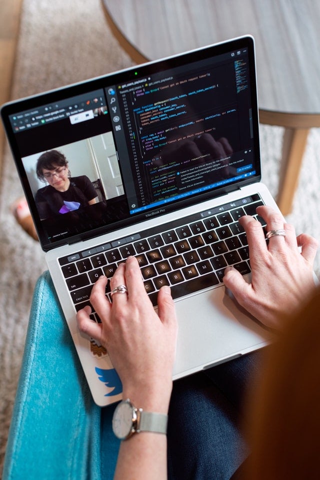 Woman coding on a laptop and being on a zoom call