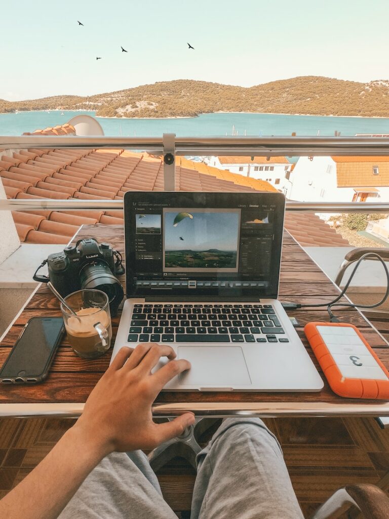 person holding MacBook Pro besides orange power bank