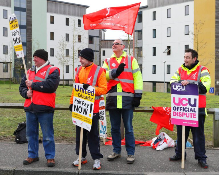 protestors holding signs asking for fair pay during the cost of living crisis.