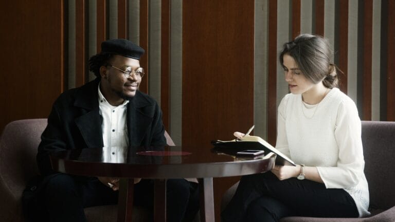 Man in Black Suit Jacket Sitting Beside Woman in White Dress Shirt