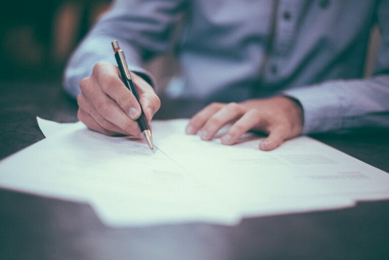 "Individual signing an employment contract, symbolizing the discussion on non-compete clause reforms.