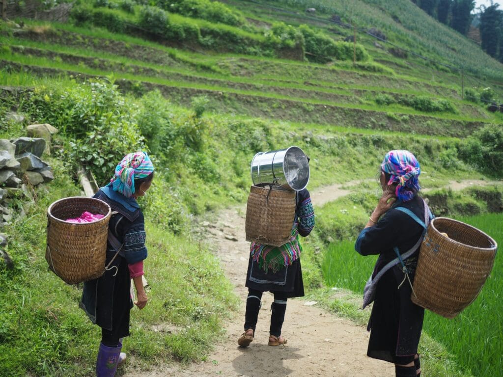 Reshaping Development to Empower Women Leaders and Entrepreneurs Globally 4 three people wearing brown wicker baskets walking on road