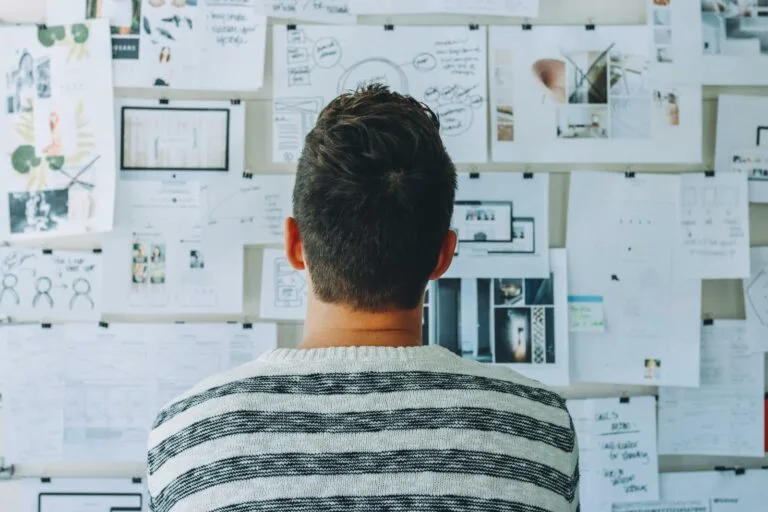 Transform Your Team’s Productivity with Smarter Management Tools 2 A man stands in front of a wall filled with creative ideas and plans. Ideal for innovation themes.