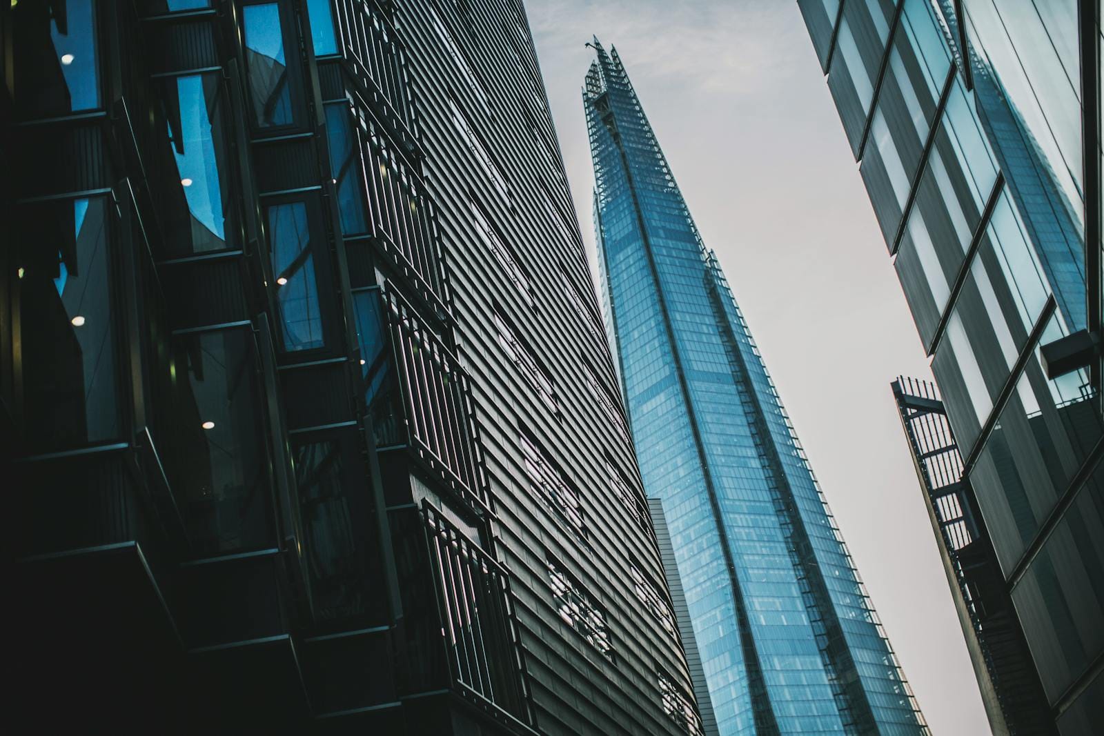 A dramatic low-angle shot of modern skyscrapers including The Shard in London.