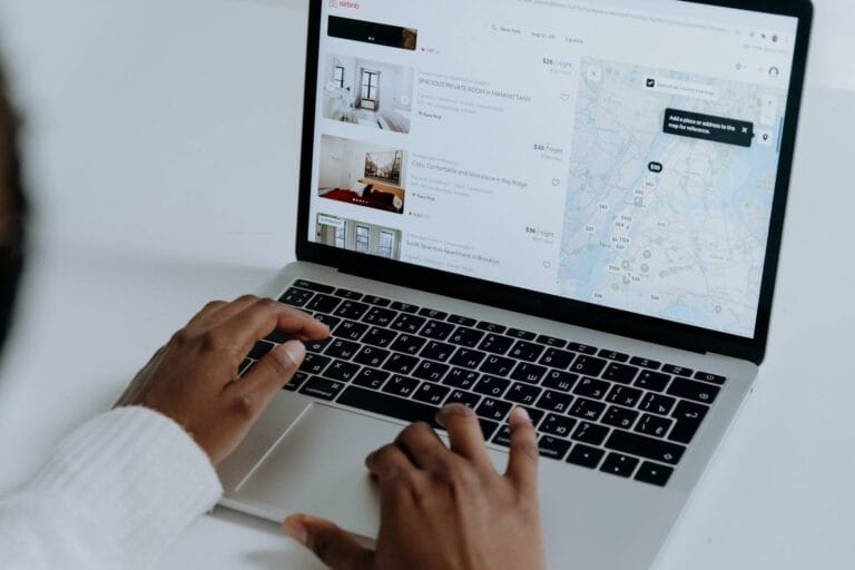 Digital Property Discovery Platforms Reshape Home Buying in 2025 10 Hands typing on laptop searching Airbnb for accommodation options with map view.