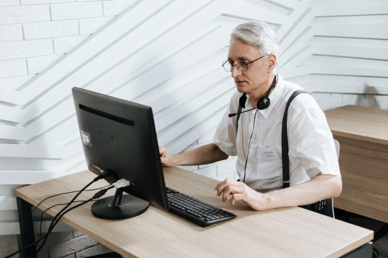Tech Hub Employment Shifts Signal New Era for Senior Professionals 2 Senior adult man working in a call center with a headset and computer.