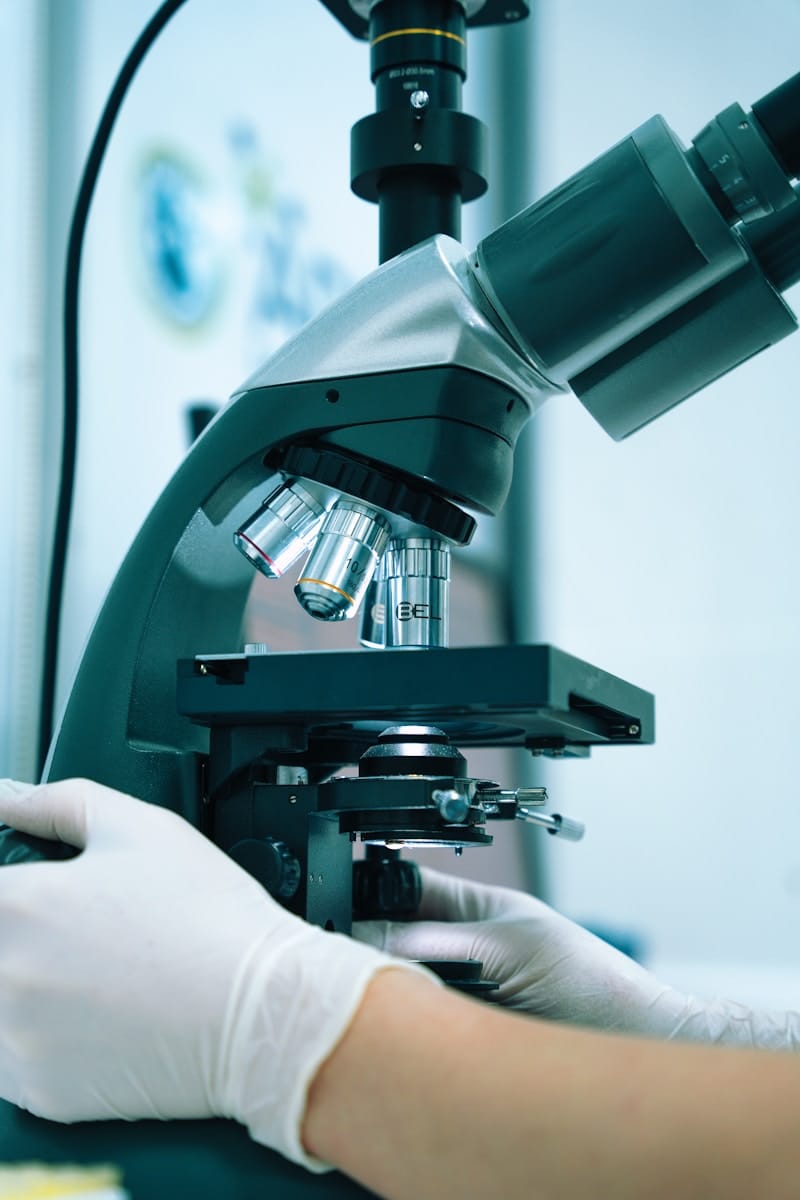 PFAS Blood Testing: What the Results Can Actually Tell You 1 a gloved hand operating a microscope in a laboratory